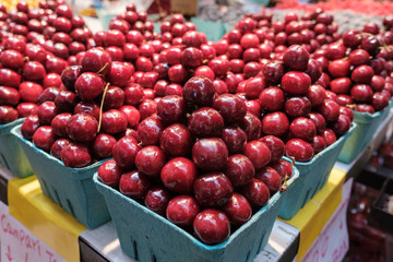 baskets of red cherries on a table for sale in a market