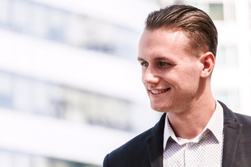 Portrait of handsome man in black suit standing outdoors