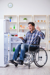 Young disabled injured man opening the fridge door 