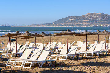 Fototapeta na wymiar Umbrellas and chaise lounges on beach. Agadir. Morocco