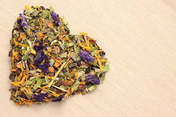 Dried herb leaves heart shaped on burlap surface