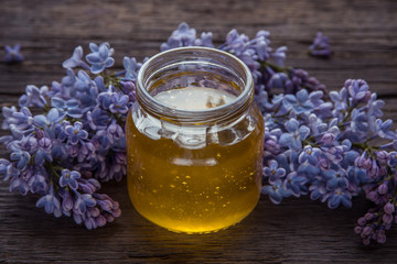 Organic honey in glass jar surrounded by spring blossom purple lilac
