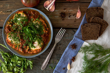 Shakshuka - jewish traditional recipe. Breakfast with fried eggs, tomato sause, pepper and green