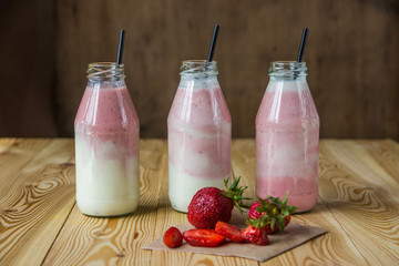 Smoothie with strawberry in bottles on wooden table