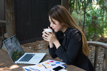 Young businesswoman on a coffee break. Using tablet computer calculator, sheet, graphs (business report) and analyst hand with her phone,  side view on wooden table