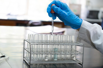 chemist dropping the clear reagent into test tube for reaction testing in chemical laboratory, with chemical equations and periodic table background.