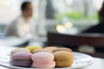 Colorful macarons line-up on garden background. Macaron or Macaroon is sweet meringue-based confection with people taking background