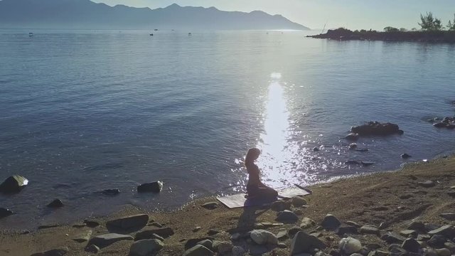 Drone Moves from Girl Silhouette in Yoga to Ocean at Sunrise