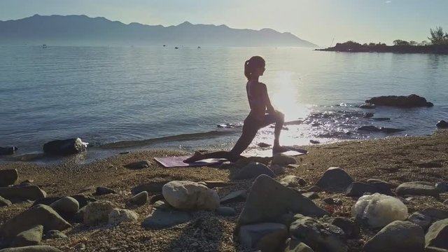 Camera Moves around Girl in Yoga Pose Crossing Sun Path on Ocean