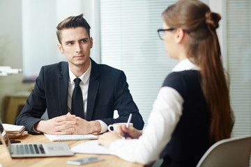 Young applicant listening to employer question during interview