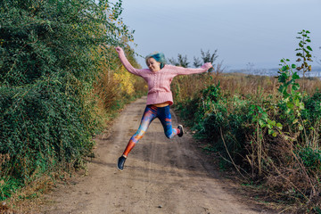 Portrait of a young woman jumping on the autumn road