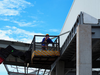 construction worker at construction site using lifting boom machinery