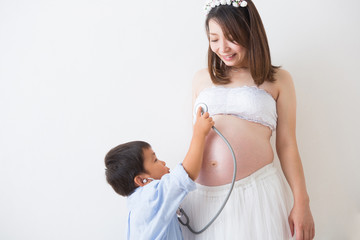 聴診器で心音を聞く男の子と妊婦さん