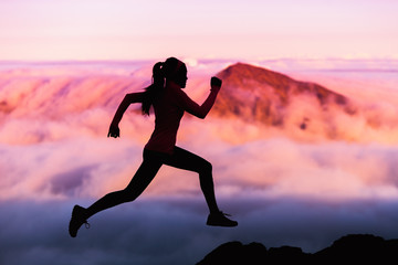 Trail runner nature landscape running woman silhouette on mountains background in cold weather with pink clouds at sunset. Amazing scenic view of peaks in altitude.