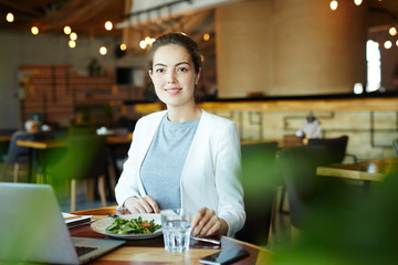 Young cheerful businesswoman having lunch in cafe