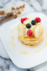 Delicious cream cheese pancakes with berry and banana on the marble table