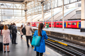Naklejka premium Osoby dojeżdżające do pracy na dworcach jadących do pracy dojeżdżają do pracy w godzinach szczytu, czekając na opóźniony pociąg. Widok tłumu na platformie i szynach.