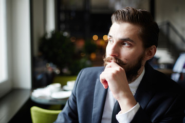 Handsome and neat young businessman contemplating in cafe