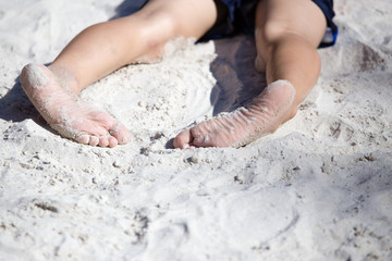 Feet of a boy playing in the sand
