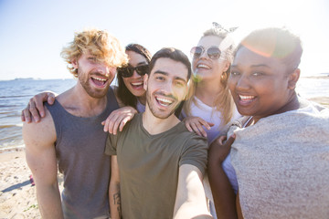 Ecstatic friends enjoying their rest on the beach and making selfie