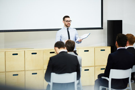 Young coach carrying out master-class for attendants in auditorium