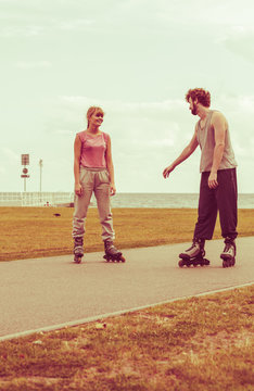 Couple wearing rollerskates looking at each other