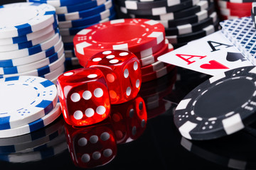 A large set of game money on a black mirror table, and two aces