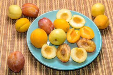 Summer fruits: apples, pears, apricots, plums on a blue plate