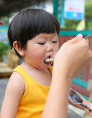 Little Asian baby eating rice by stainless spoon.