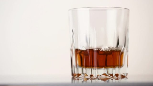 Faceted glass filled with whiskey and ice cubes
