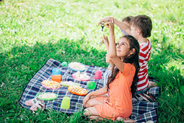 Cute little girl and her older sisters blows at colorful spinner in the garden.