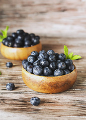 fresh bilberries or blueberries in small wooden bowls, selective focus