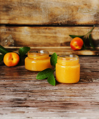 Apricot jam in small glass jars with fruits, selective focus