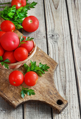red tomatoes on a wooden board with parsley. country style