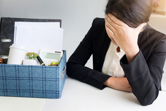 sadness pretty female office worker is fired packing personal belongings sitting on working desk feeling upset and thinking future job.