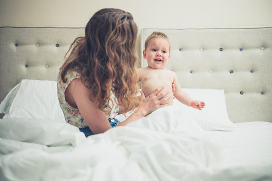Mother playing with baby in bed