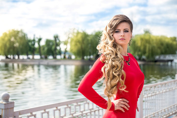 portrait of smiling woman in red dress near lake, in summer