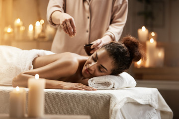 Obraz na płótnie Canvas Tender african girl relaxing enjoying healthy spa massage with oil.