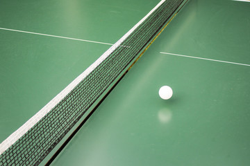 Table tennis, ping-pong table and the white ball on a green table.