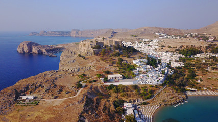 Obraz premium Aerial drone photo of famous beach of Lindos with turquoise waters and iconic ancient Acropolis - village of Lindos, Rodos island, Aegean, Dodecanese, Greece