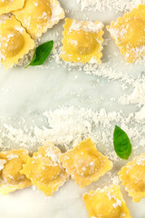 Overhead photo of ravioli with flour and basil leaves