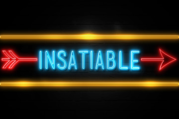 Fototapeta premium Insatiable - fluorescent Neon Sign on brickwall Front view