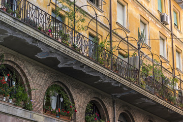 beautiful facade of an old building on a street in Rome, decorated with flowers