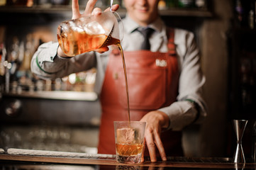 Barman in bar interior making alcohol cocktail.