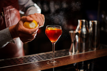 Bartender is adding lemon zest to the cocktail at bar counter. Selective focus
