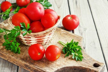 red tomatoes on a wooden board with parsley. country style