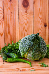 Savoy cabbage with pepper and greens on wooden background