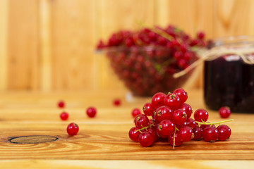Jar with jam of red currant on a wooden background