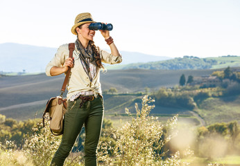 woman hiker in Tuscany looking into distance through binoculars