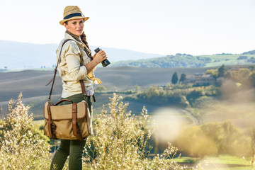 active woman hiker hiking in Tuscany with binoculars